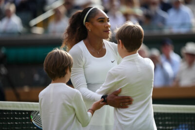 Serena Williams en tenue de tennis sur le court de Wimbledon, prête à compétitionner en simple.