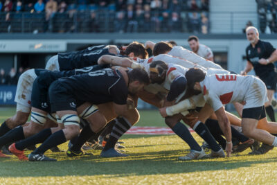 Quatre équipes de rugby en compétition, maillots distincts, stade bondé de supporters
